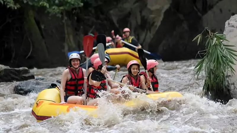 Guests paddling through a fast river section in a yellow raft