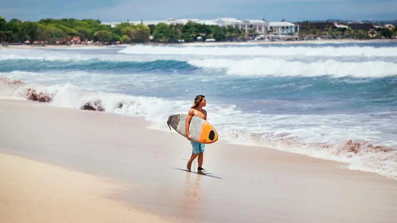 Beginner surfer walking along Kuta Beach