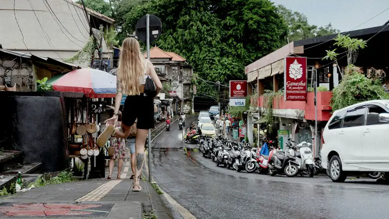 Traveler walking along a narrow sidewalk in central Ubud
