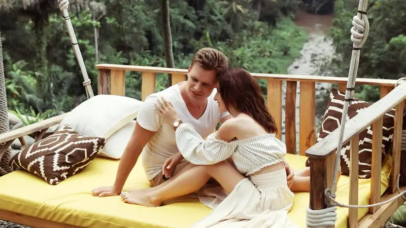 Couple relaxing on a daybed overlooking a green valley in Ubud