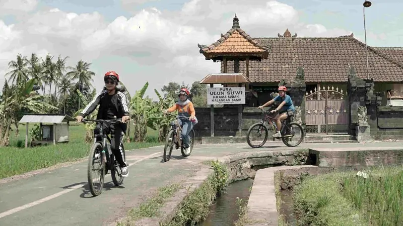Cyclists passing a village temple area in Ubud