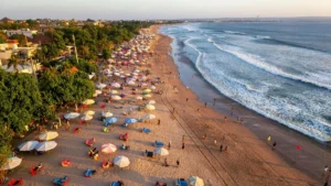 Aerial view of Kuta Beach with umbrellas and waves in Bali