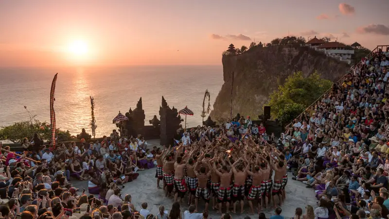 Kecak dancers perform at Uluwatu with sunset and ocean cliffs